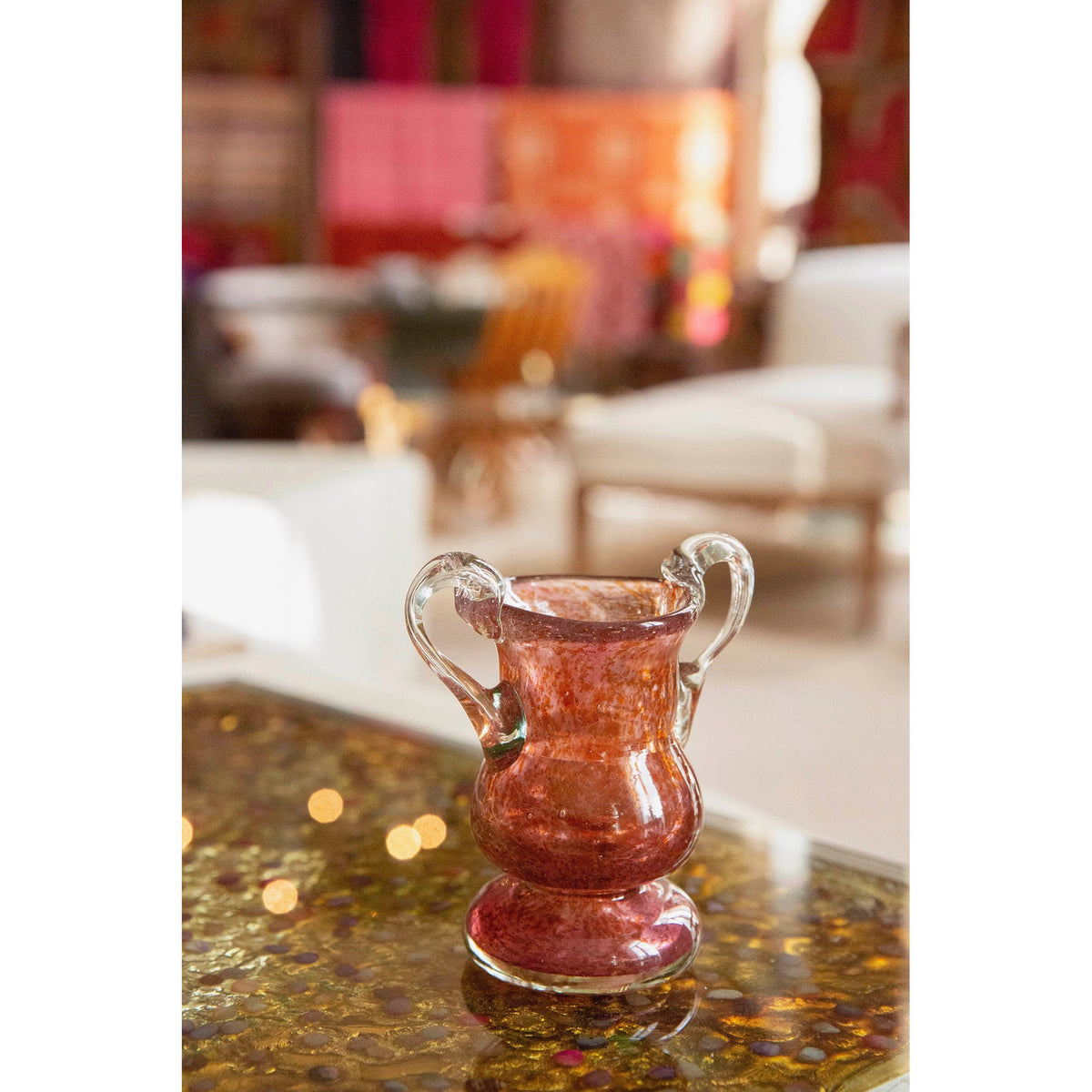 Rose lass vase on a gold table in a colorful room