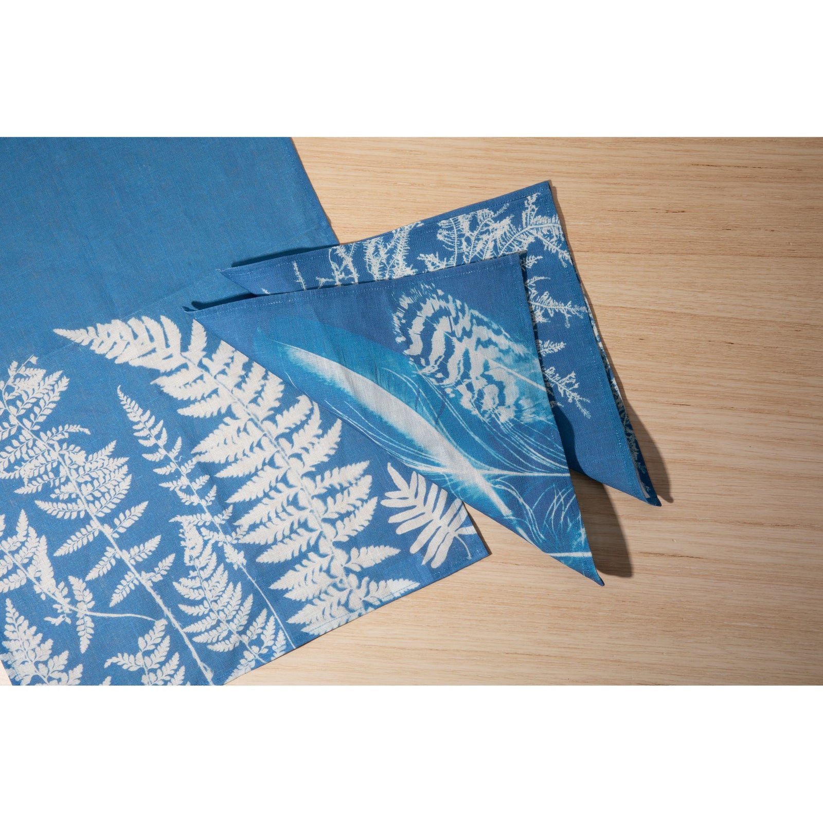 A blue tea towel with a white leaf pattern hanging on a clothesline.