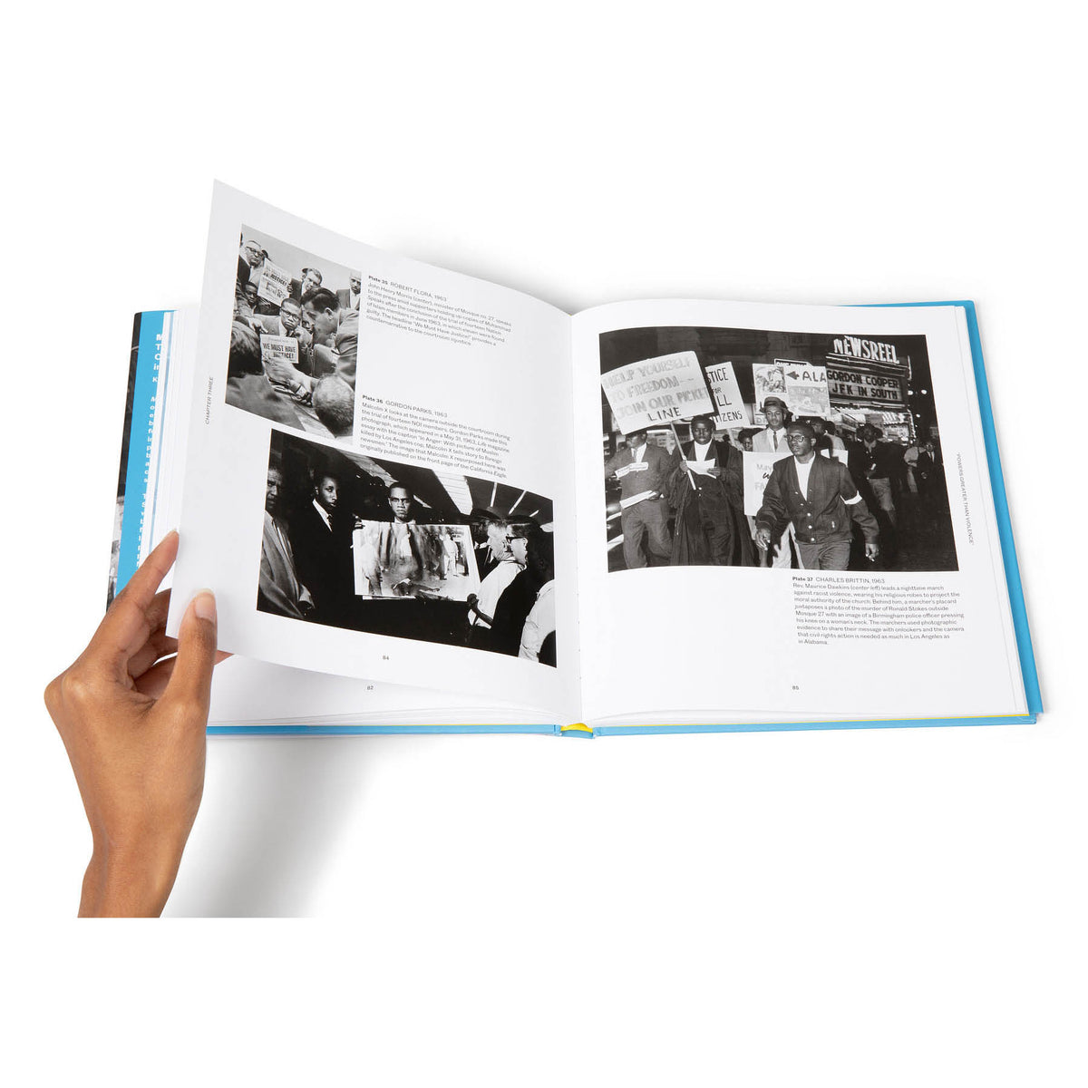 Open book with black and white photos and text held by a hand on a white background