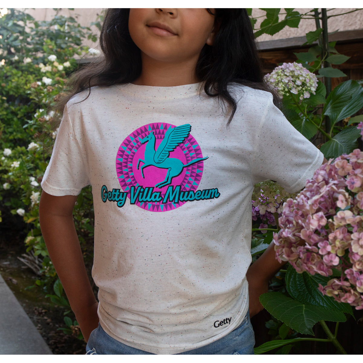 Child wearing a t-shirt with Getty Villa Museum logo in a garden setting
