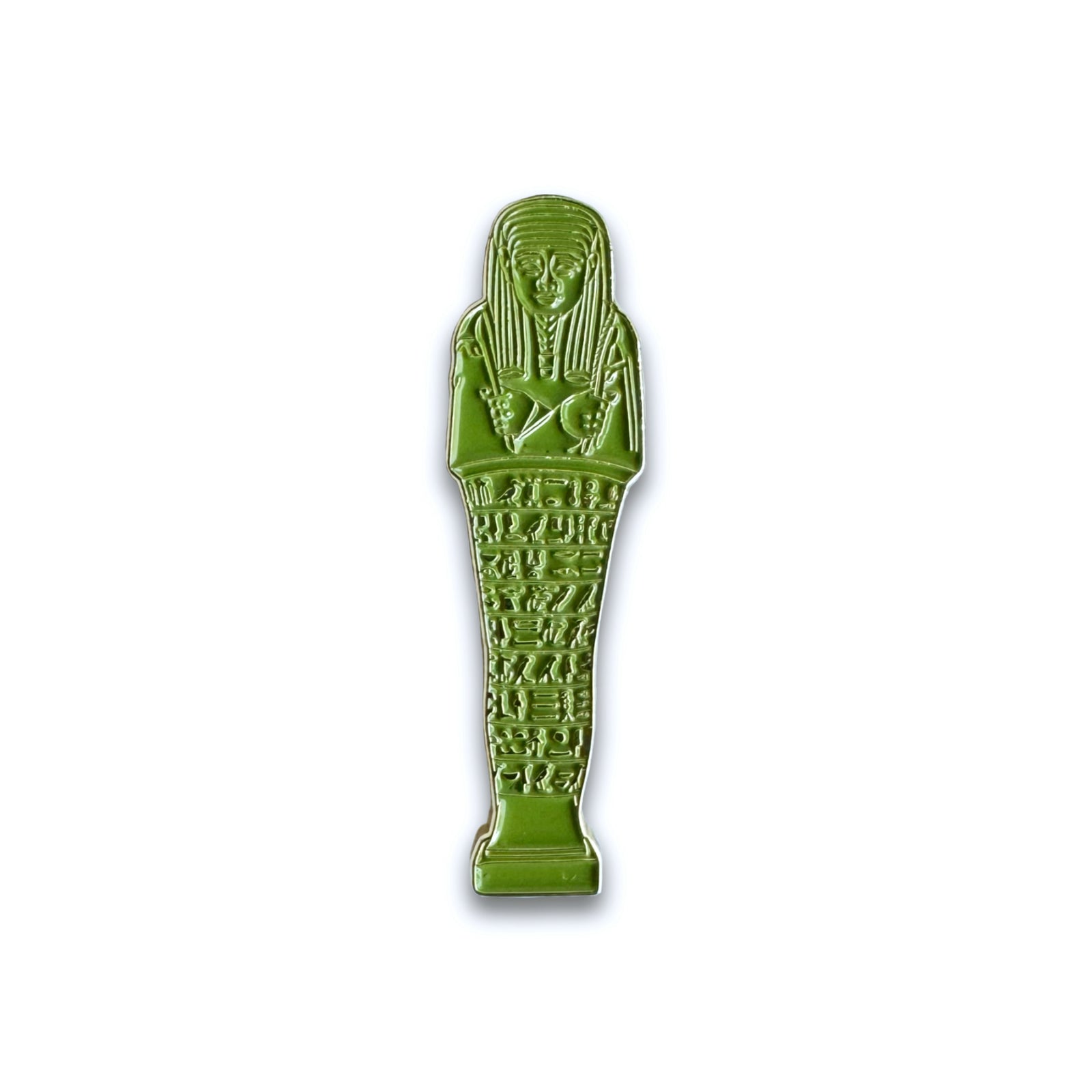 An enamel pin shaped like an Egyptian ushabti funerary figurine, in green color, standing on a rectangular base with a hieroglyphic inscription.