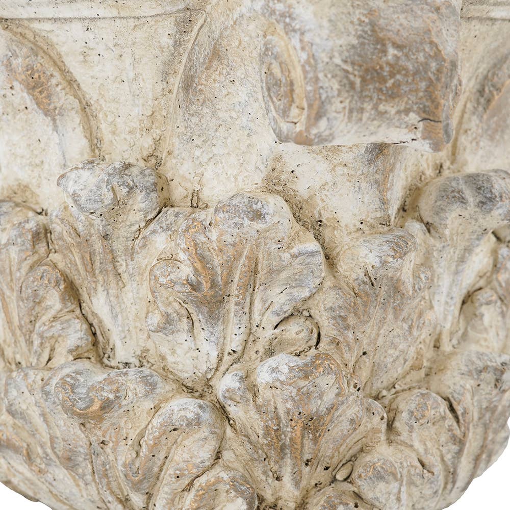 Close-up of a carved stone or concrete decorative element with a textured, weathered finish in light beige and gray tones.