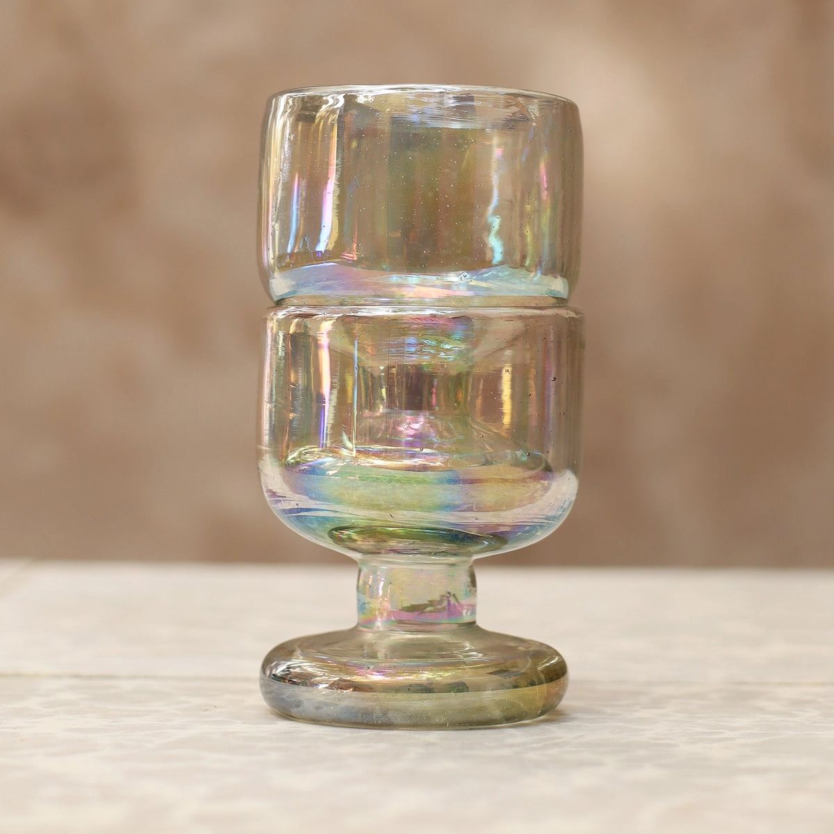 Iridescent glass goblet on a textured surface with a blurred background
