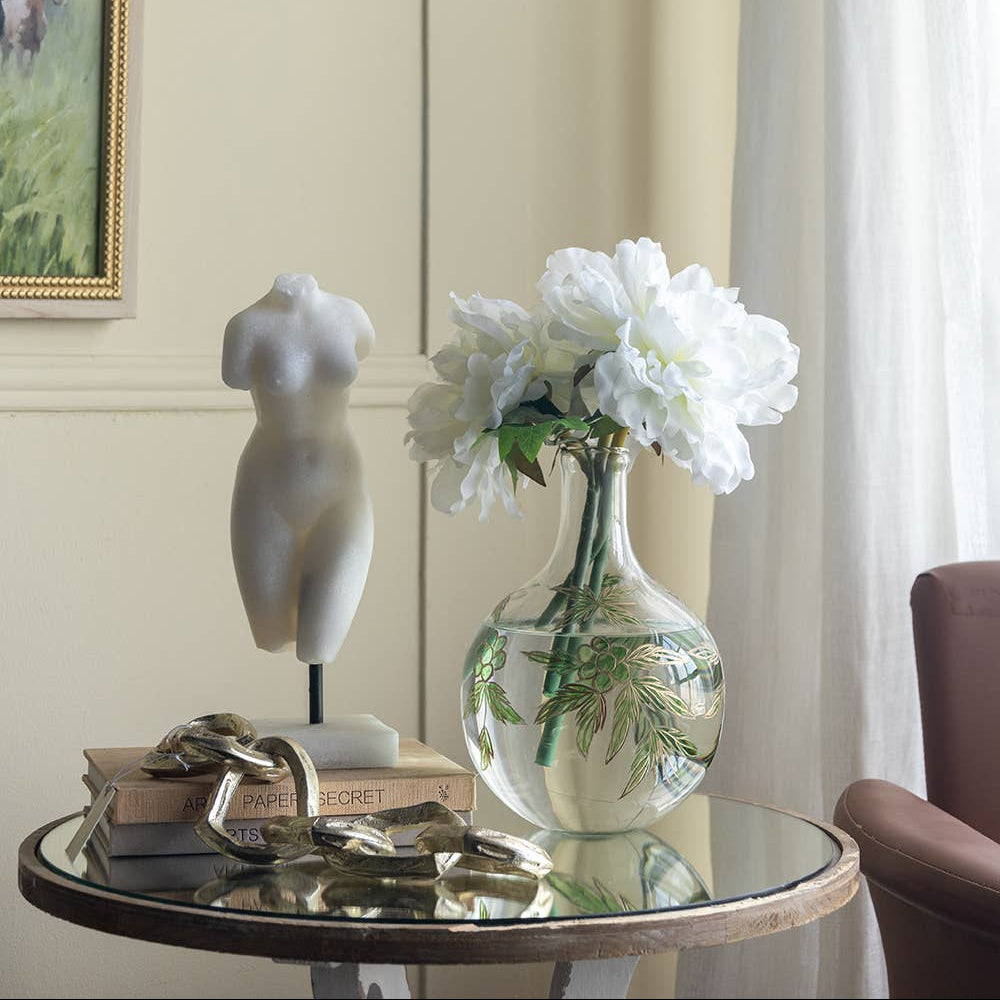 Nude female sculpture on a table next to flowers