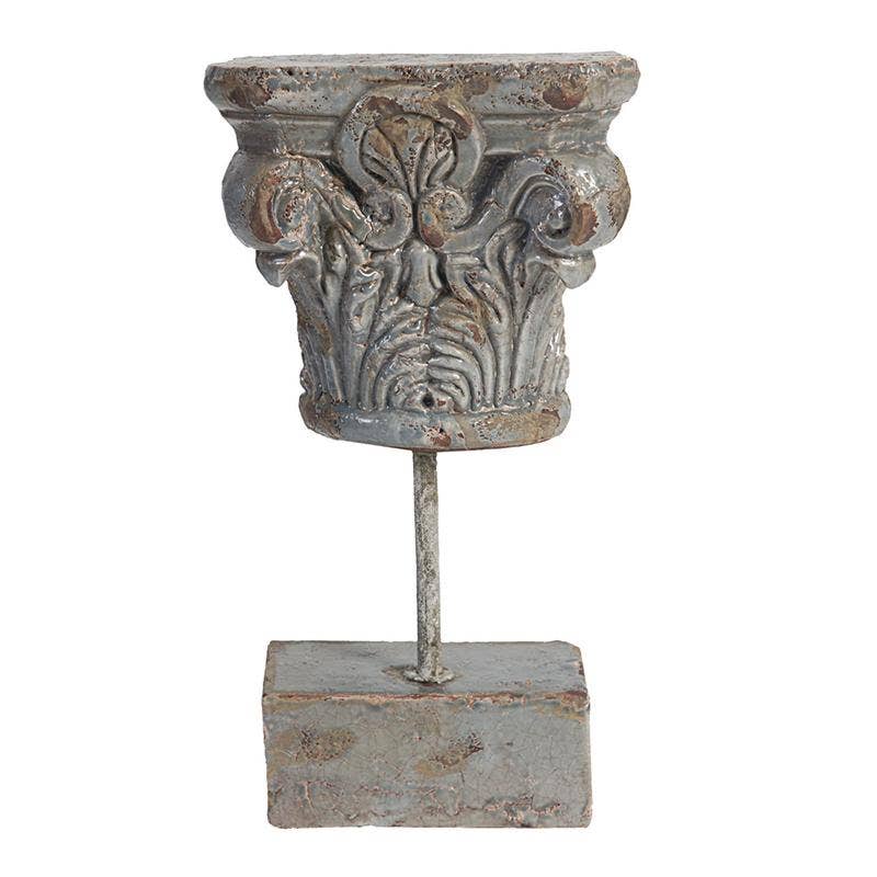 Decorative metal column capital on a stand with a white background