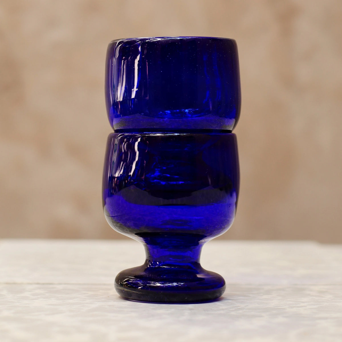 Blue glass goblet on a textured surface with a neutral background