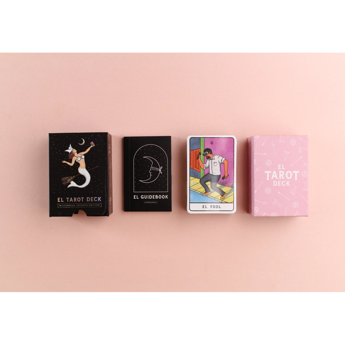 Four items from the 'El Tarot Deck' set arranged in a row on a solid pink background: the black illustrated deck box, the black guidebook, a single illustrated tarot card, and a pink card deck box.