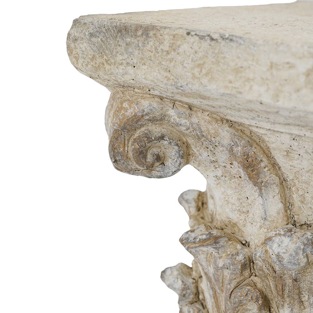 Close-up of a carved stone or plaster decorative architectural element with a scrolled corbel detail and weathered beige-gray texture on a white background.