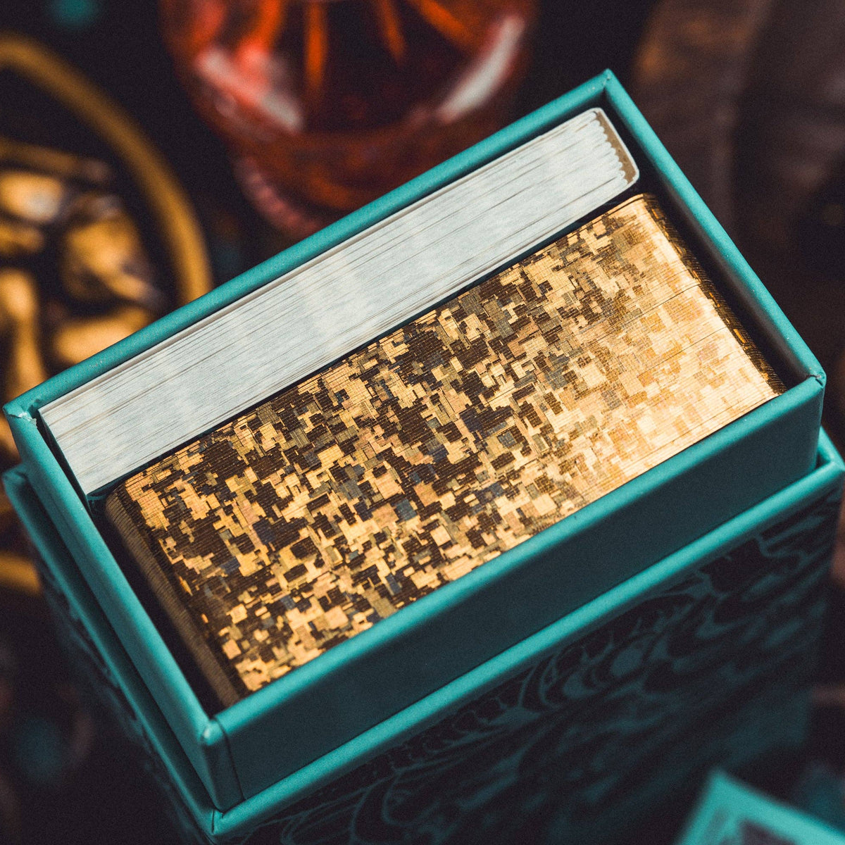 Gold and silver rectangular object in a teal box with a blurred background