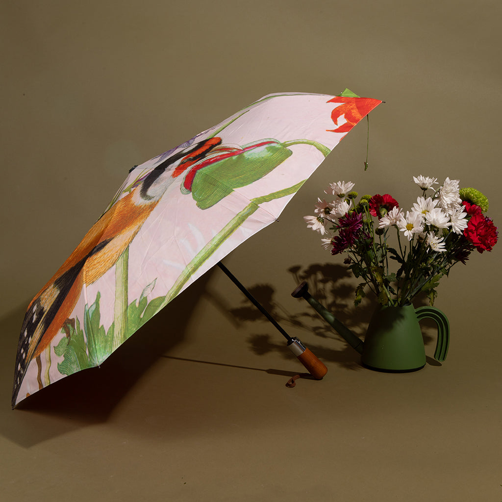 Umbrella with floral design next to a vase of flowers on a brown background