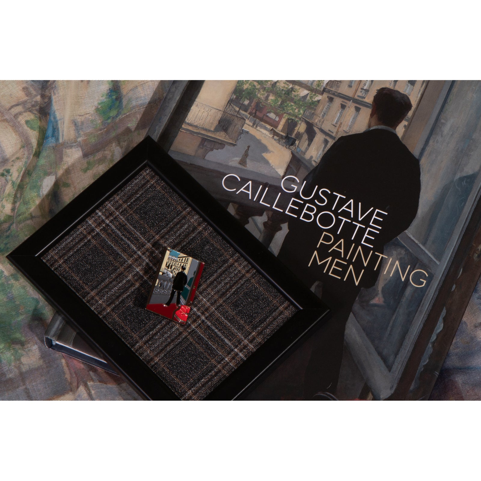 A packaged enamel pin with a painting of a young man at his window, with red accents on the shirt and a white background.