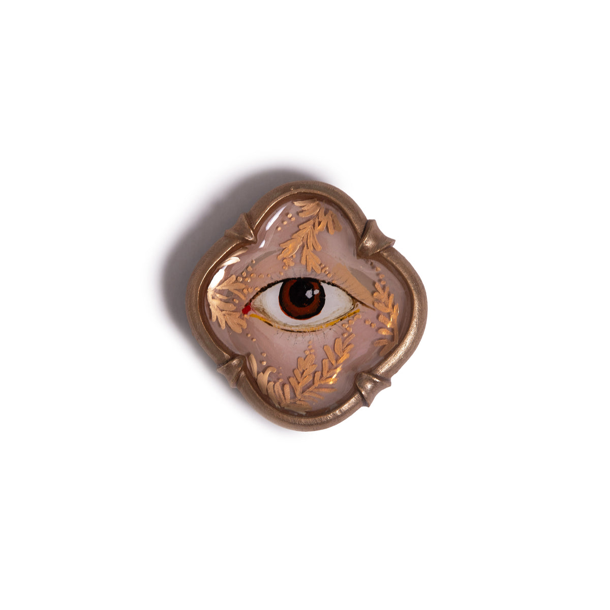 Decorative brooch with eye design on a white background