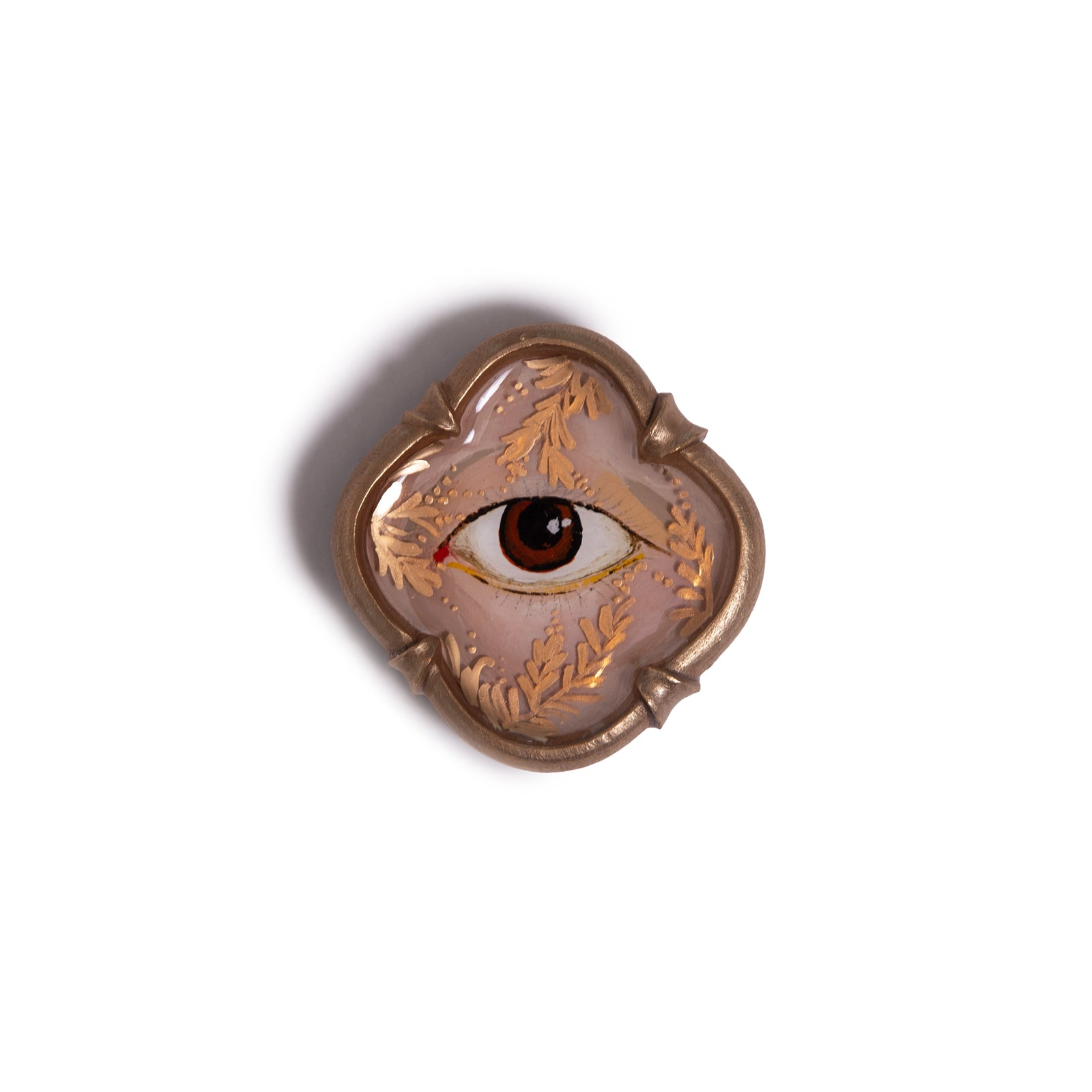 Decorative brooch with eye design on a white background