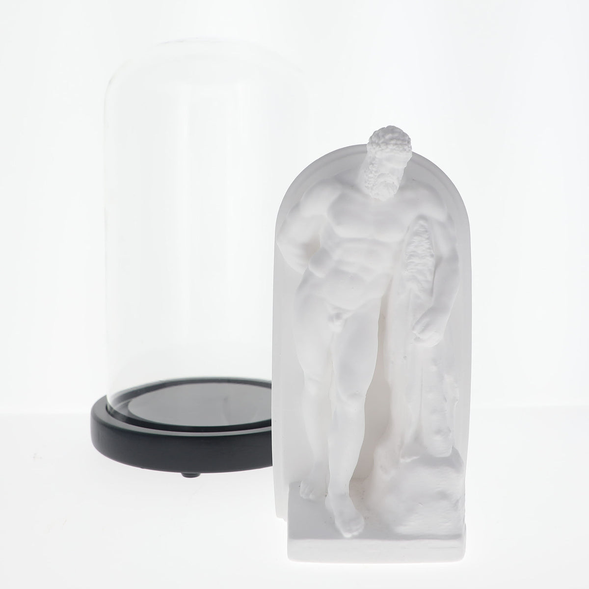 A frosted white classical statue of a muscular male figure in an arched niche, shown next to a clear glass dome with a black base on a white background.
