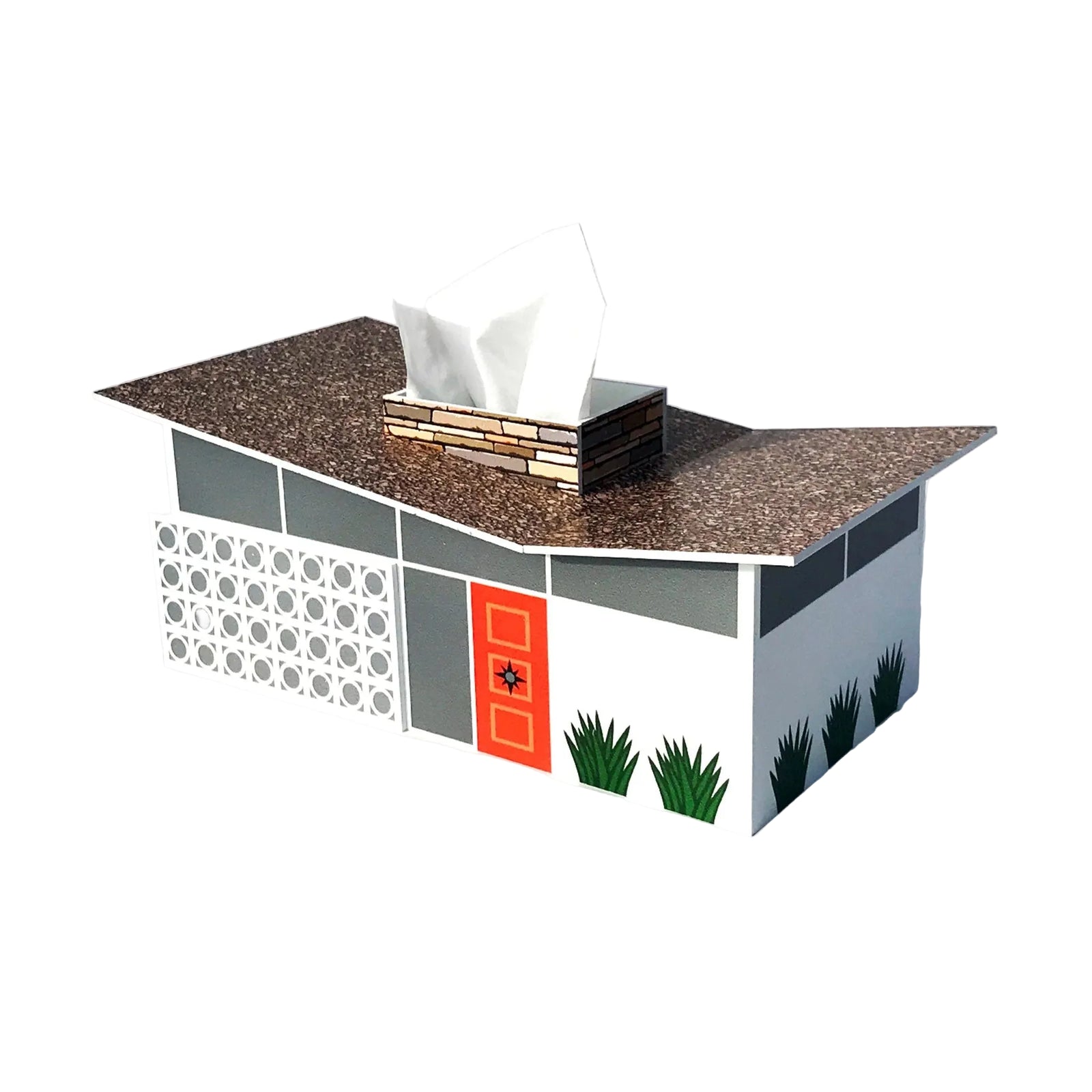 A tissue box cover shaped like a modern house, with a tissue protruding from a brick-like box on its roof. The house design features a brown speckled roof, white and gray walls, a bright orange door, and small green plant illustrations along the base, shown on a light gray background.