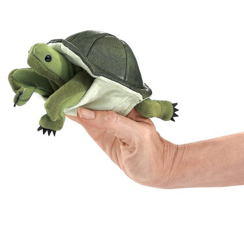 Hand holding a green turtle plush toy against a white background