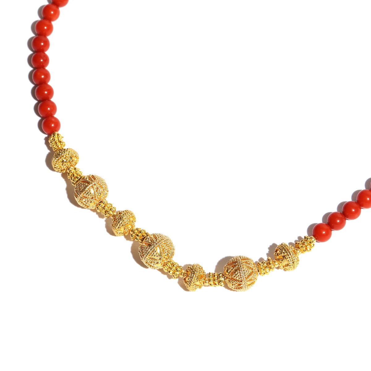 Necklace with red beads and gold filigree on a white background