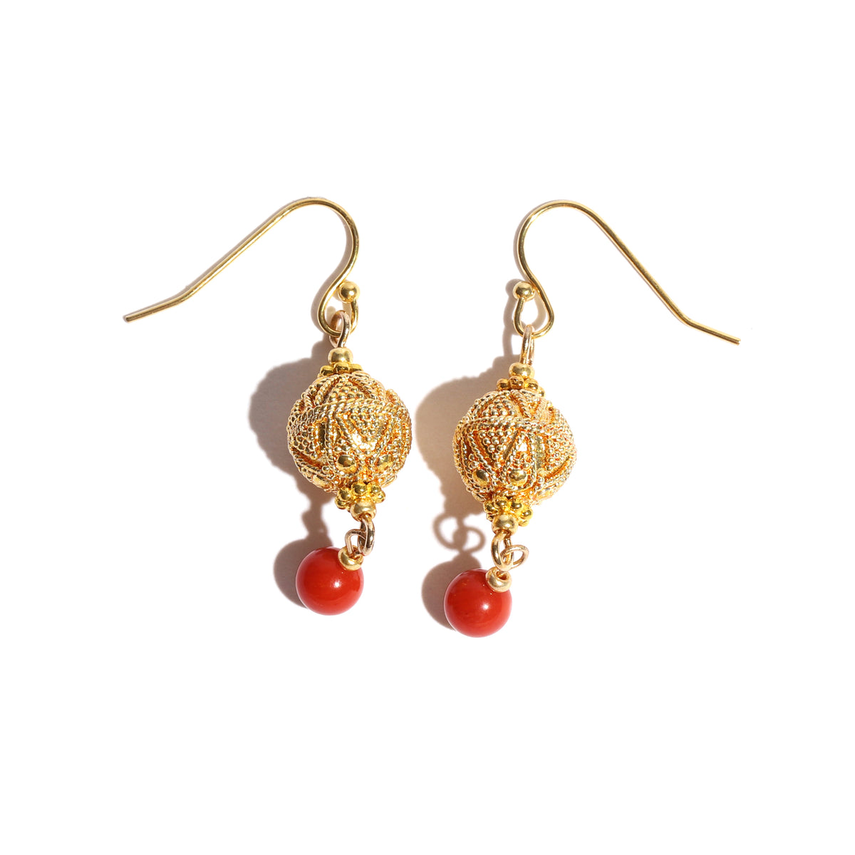 Gold earrings with red beads on a white background