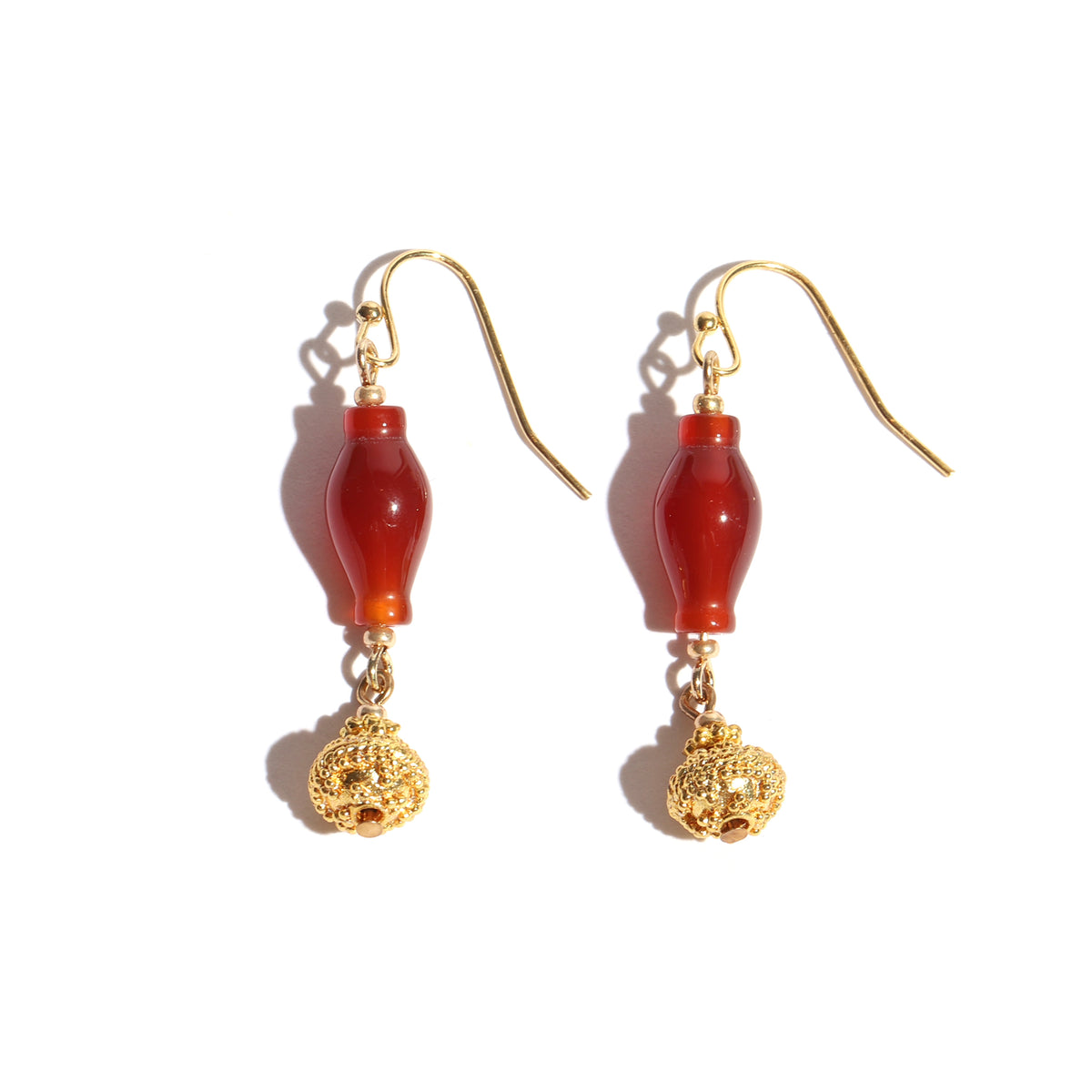 Pair of earrings with red beads and gold accents on a white background