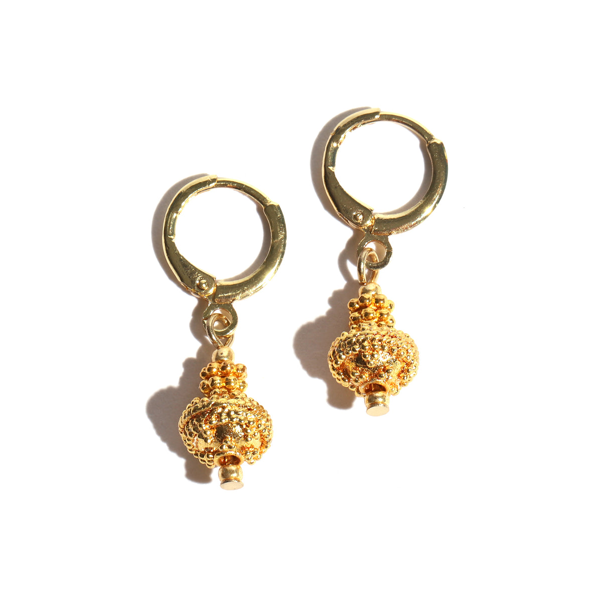 Pair of gold hoop earrings with spherical charms on a white background