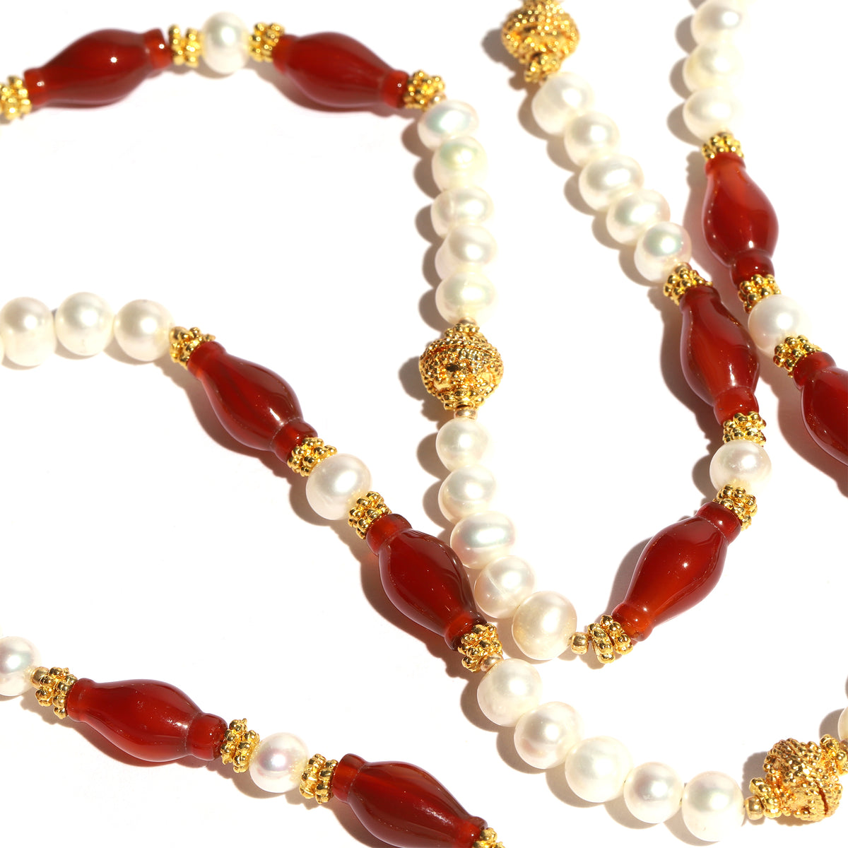 Necklace with red beads, white pearls, and gold accents on a white background
