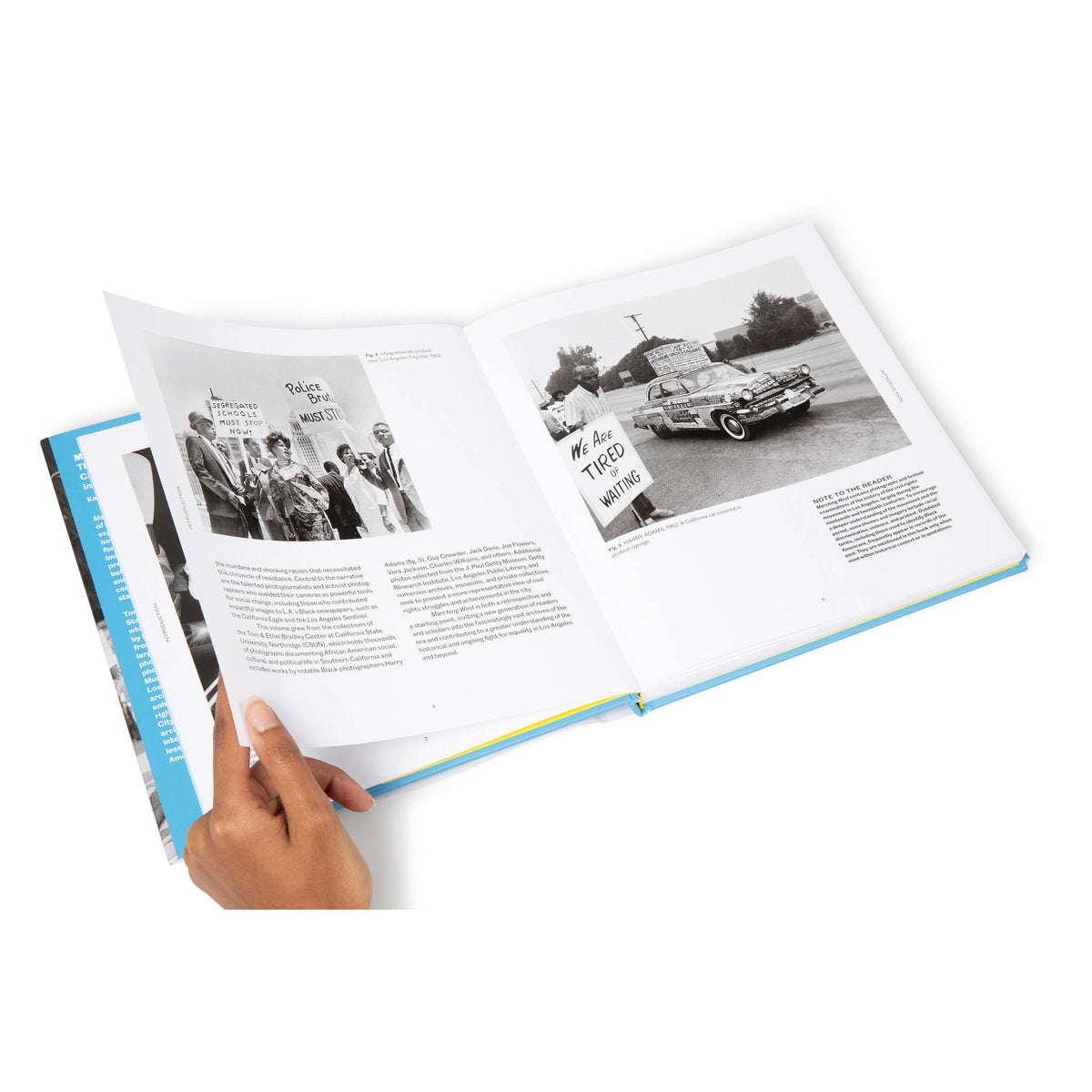 Open book with black and white photos and text held by a hand on a white background