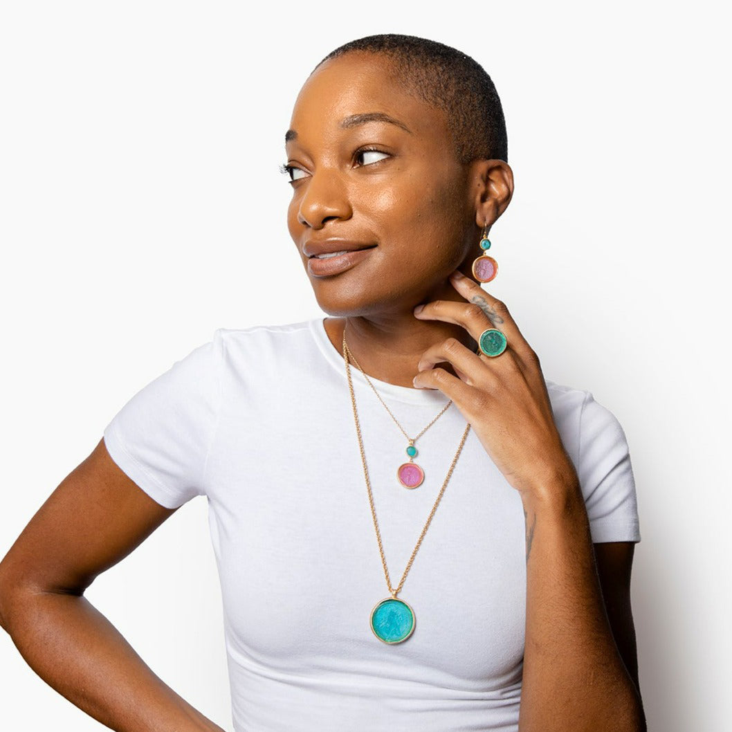 A pair of dangle earrings featuring circular glass motifs in pink and blue, with gold accents.