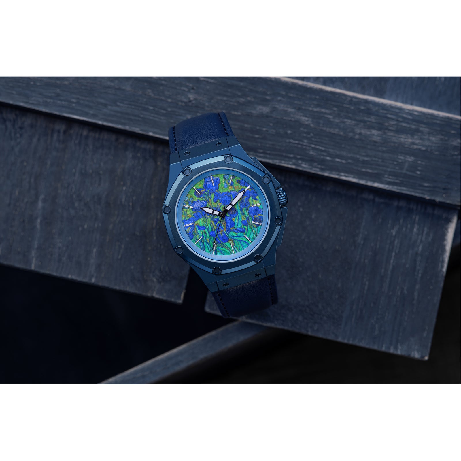 A blue stainless steel watch with a blue leather band featuring a floral pattern on the watch face, specifically resembling the 'Irises' artwork by Vincent van Gogh.