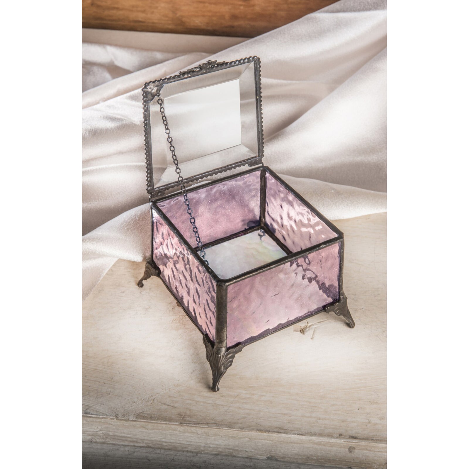 Pink square glass jewelry box with metal details and a hinged lid