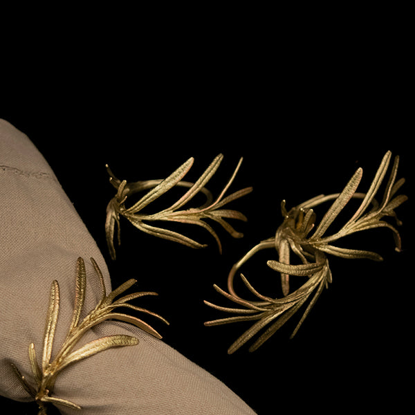 A golden napkin ring with a rosemary leaf design against a white background.