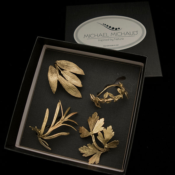 A set of 4 napkin rings designed to resemble herbs, with gold finishes, displayed against a white background.