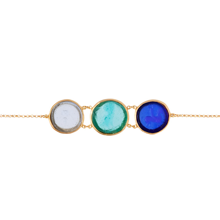 A bracelet with three circular glass coin motifs in blue, green, and white, set in gold-colored frames, linked together on a gold chain.